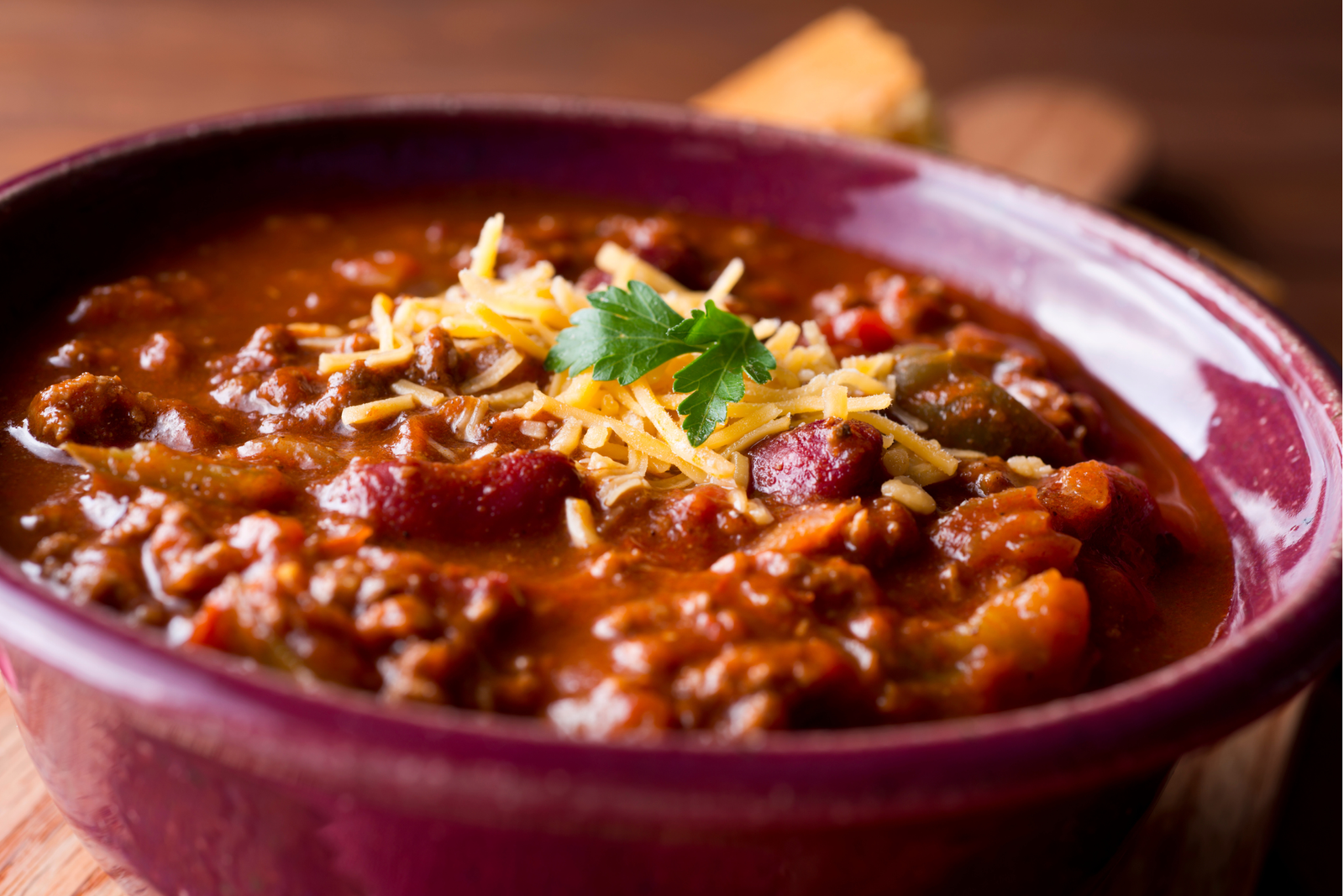 A bowl of chili and beans with some shredded cheese on top