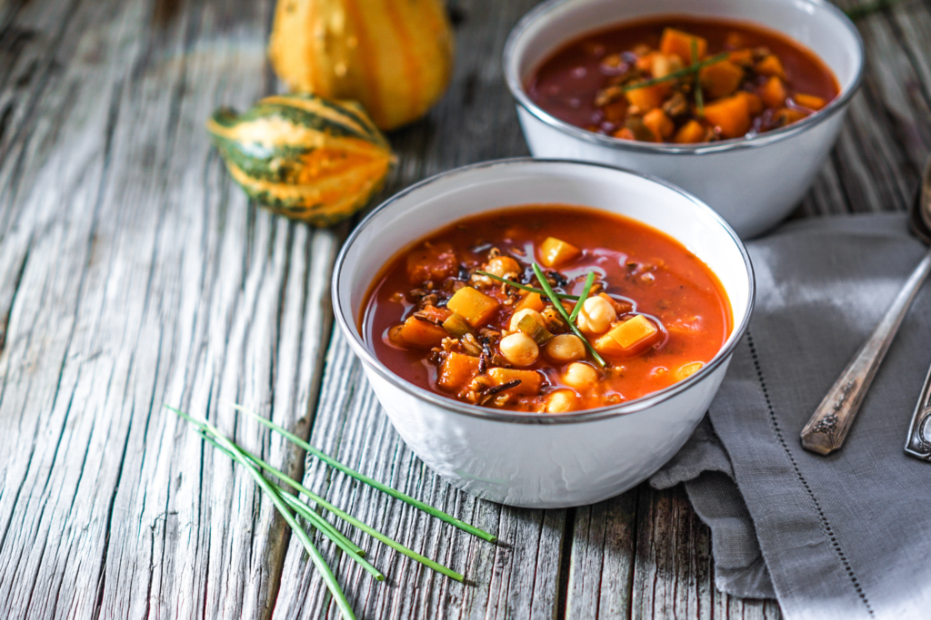 chunks of pumpkin and chickpeas sit in a heart tomato base chili