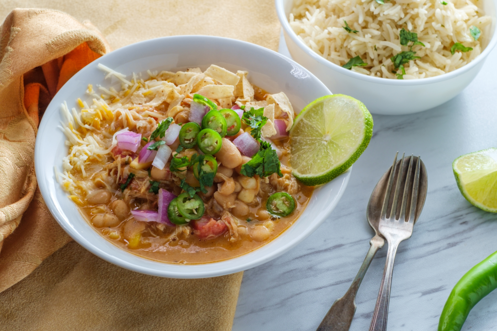 white chicken chili topped with red onions and jalapeños