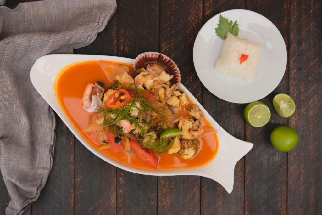 seafood chili, a mix of shrimp, crab, and fish chili in a fish-shaped dish, with a shell and lime garnish