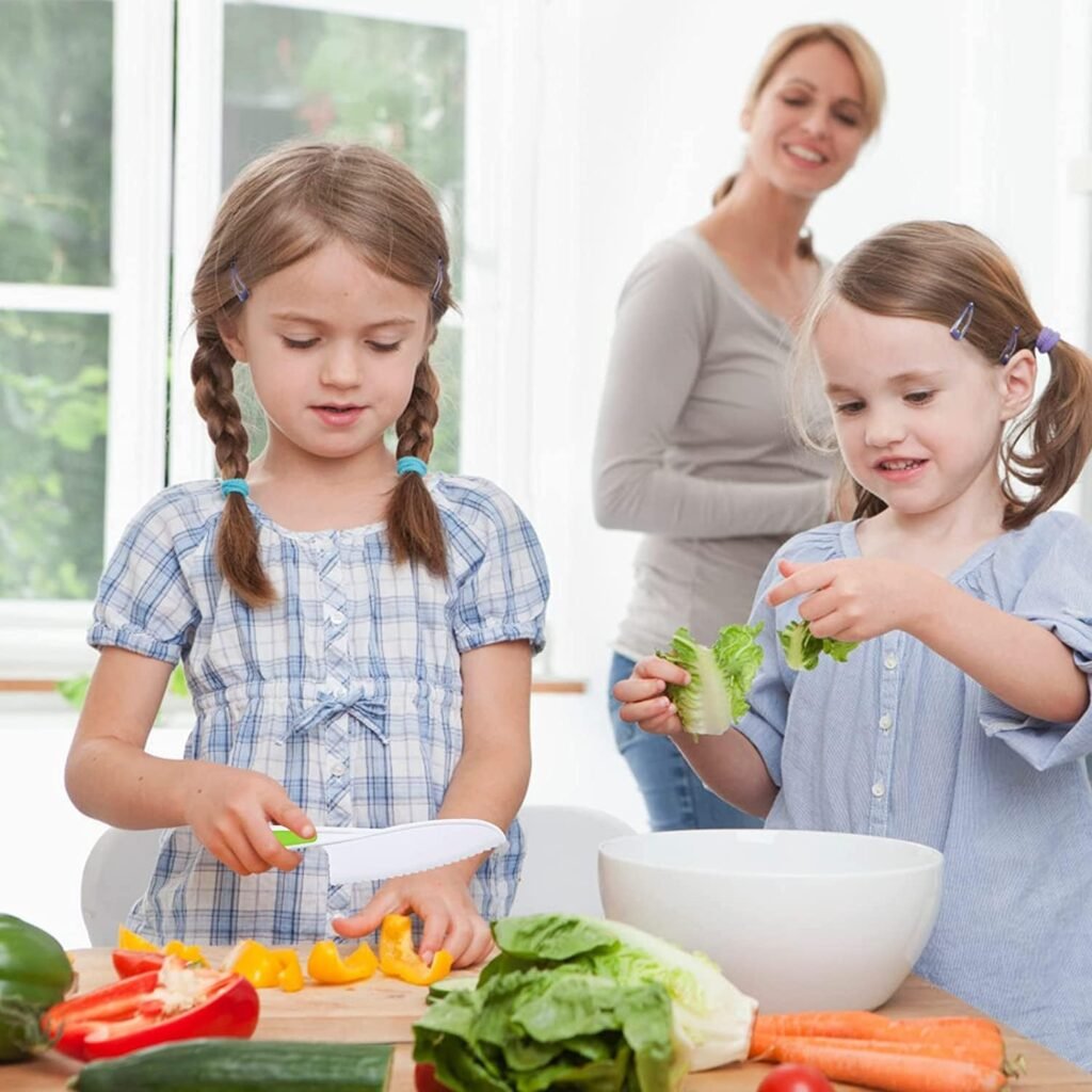 two young girls cutting vegetables with the kids knives while their mom watches from a distance